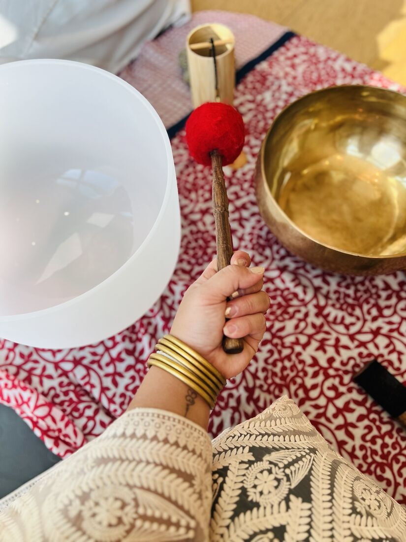 Felt mallet held between a crystal bowl and a brass bowl